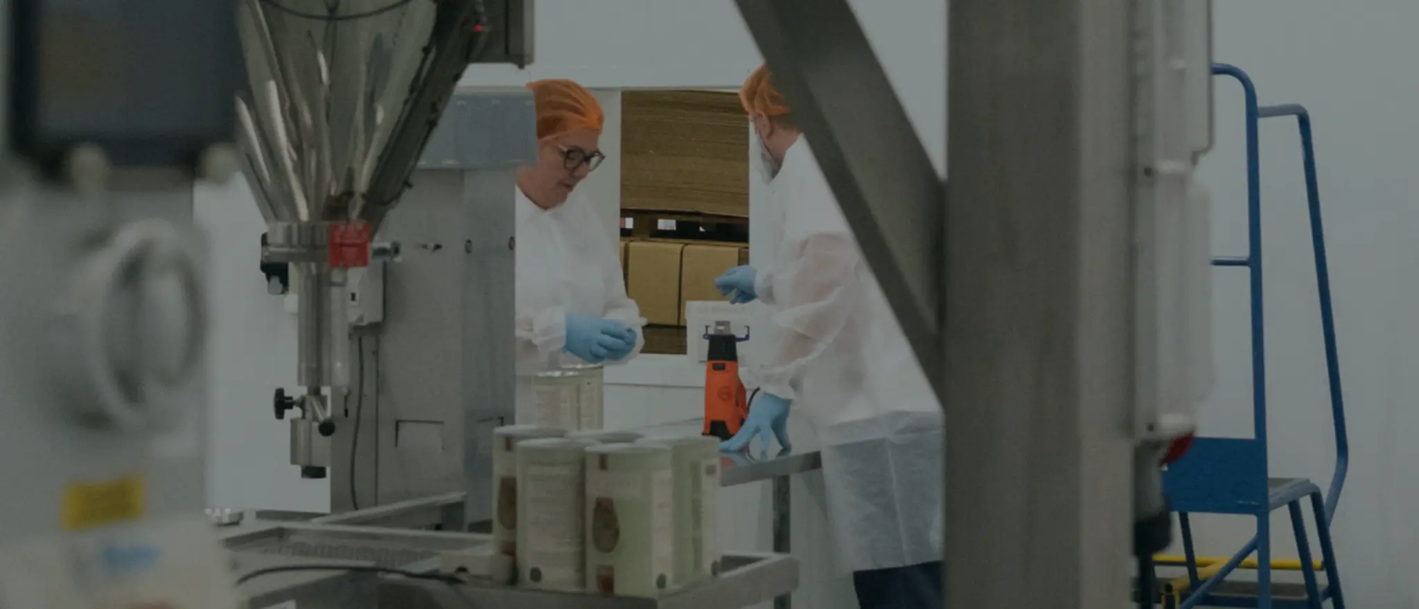 Rawcreation production technicians filling and heat-sealing labelled supplement tubs on the line in Great Yarmouth