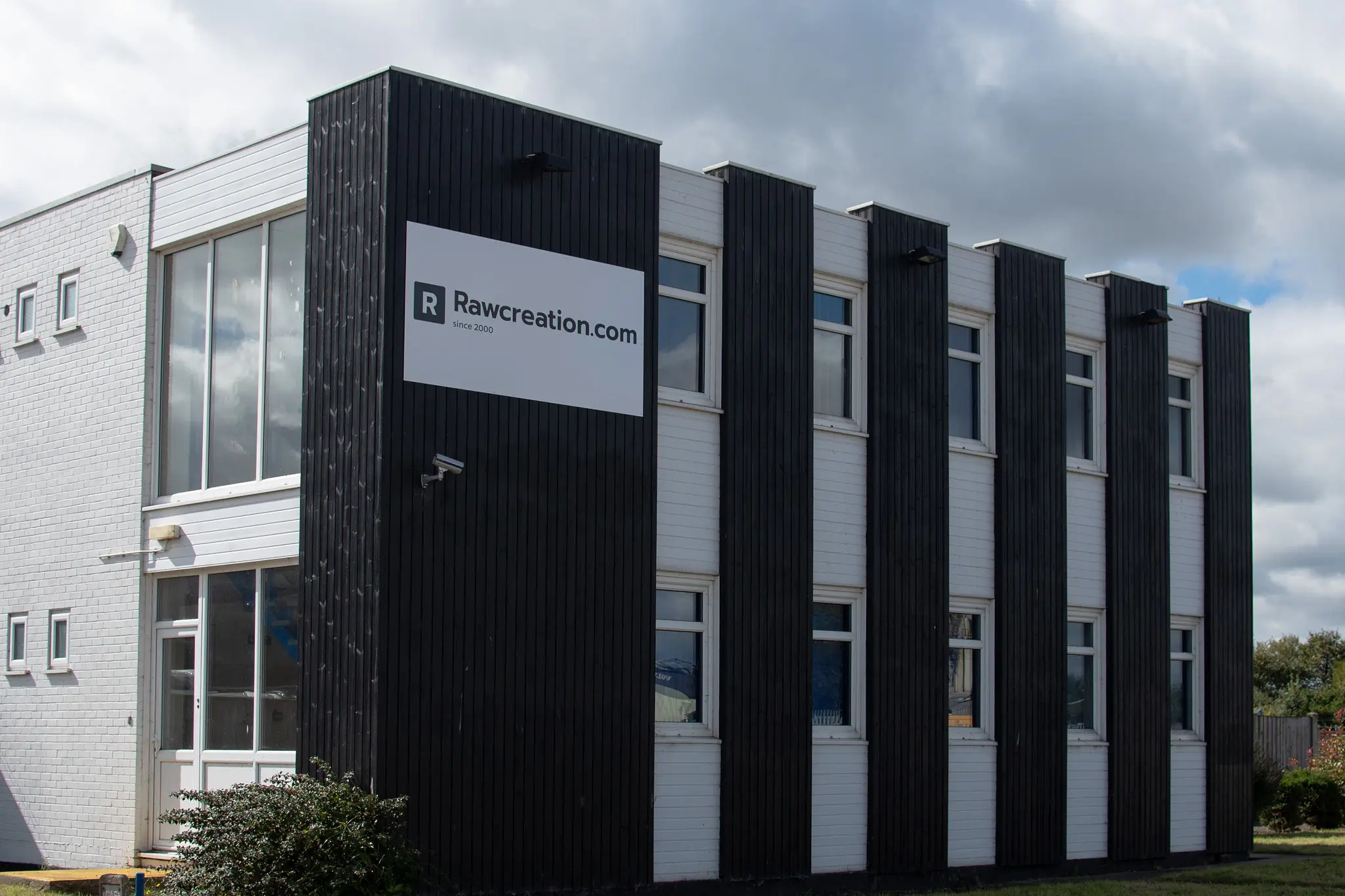 The Rawcreation.com sign on the black-clad corner of the factory building